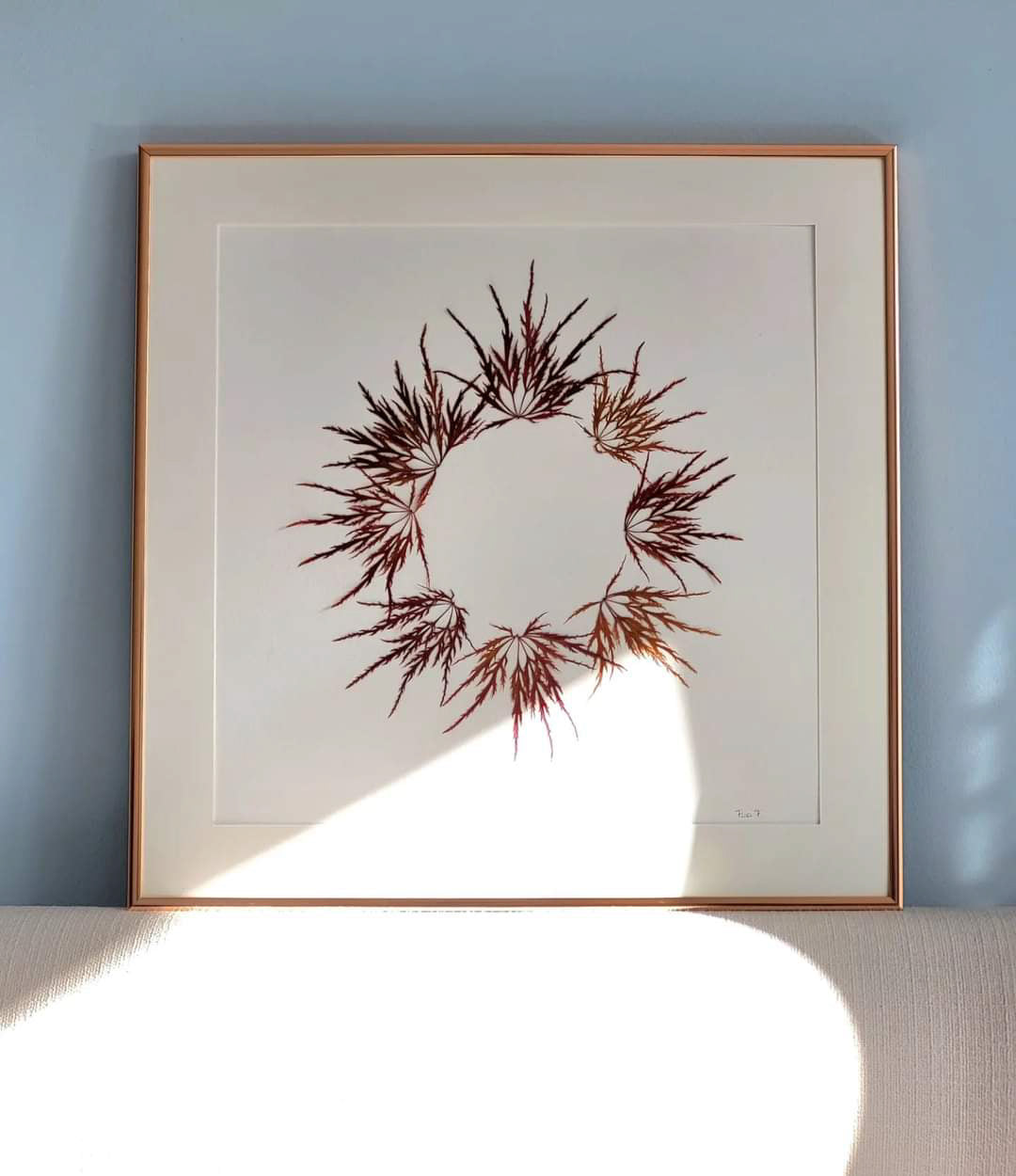 Herbier d'Art fait avec des feuilles d'érable japonais en forme de couronne. Style: épuré. Décoration murale élégante, épurée, moderne, naturelle. Feuilles automnales de couleur cuivre. Cadre haut de gamme en aluminium fin de couleur cuivré. Couronne d'automne.