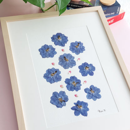 Herbier d'art encadré, réalisé à partir de fleurs de delphinium bleu et de pétales de gomphrena globosa, tous issus de sources respectueuses de l'environnement. Cadeau parfait pour la fête des mères. 